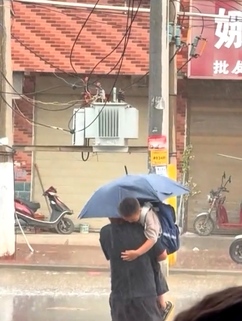 ภาพพ่อกางร่มไปรับลูกกลางสายฝน กลายเป็นไวรัลทำคนหลุดขำ ภาพพ่อกางร่มไปรับลูกกลางสายฝน กลายเป็นไวรัลทำคนหลุดขำ