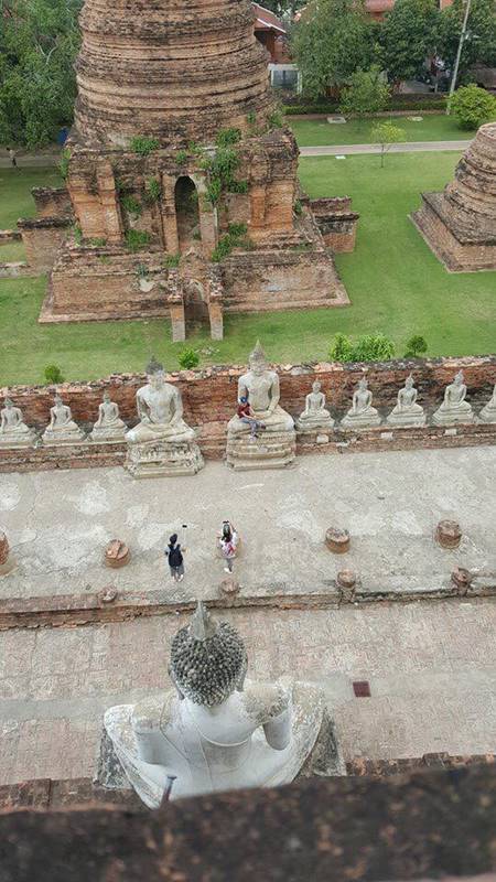 นักท่องเที่ยวสาวนั่งบนพระพุทธรูป