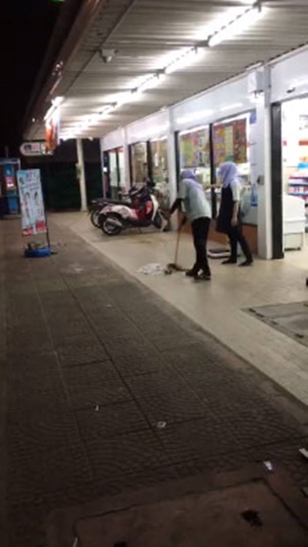พนักงานร้านสะดวกซื้อกวาดขยะทิ้งบนถนน