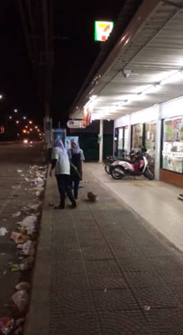 พนักงานร้านสะดวกซื้อกวาดขยะทิ้งบนถนน